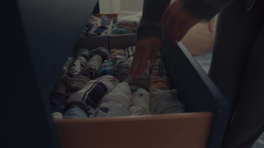 Woman organizing baby clothes in a drawer