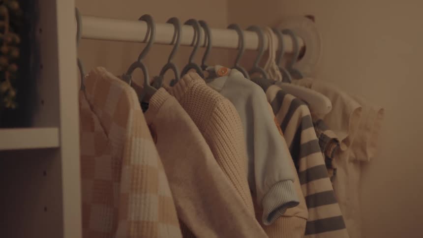 A wardrobe with a series of knitwear hanging on hangers alongside some casual clothing
