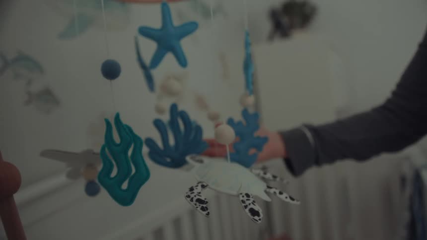 Hand holding a mobile with stars and sea elements in a nursery