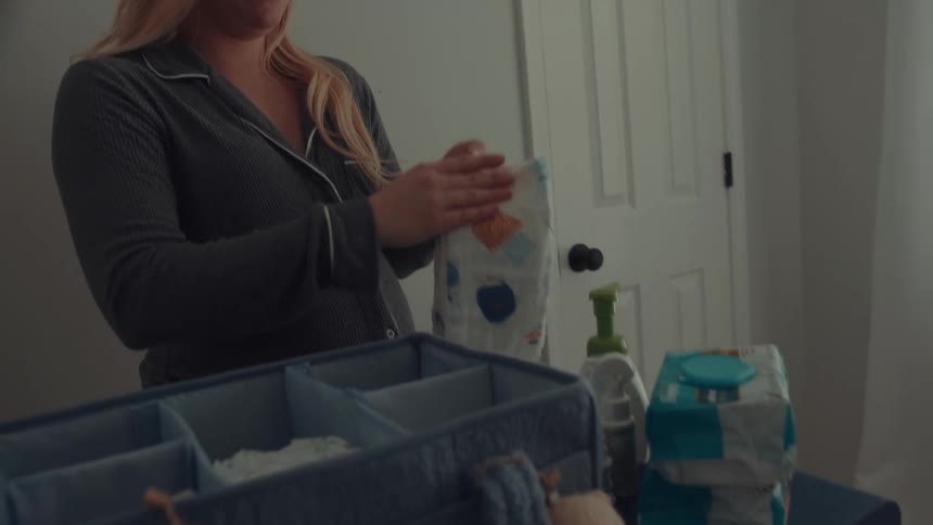 Woman organizing diapers and baby items on a changing table
