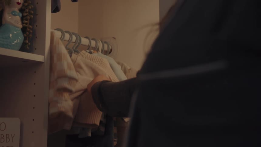 Woman stores lightcolored plaid shirt in closet