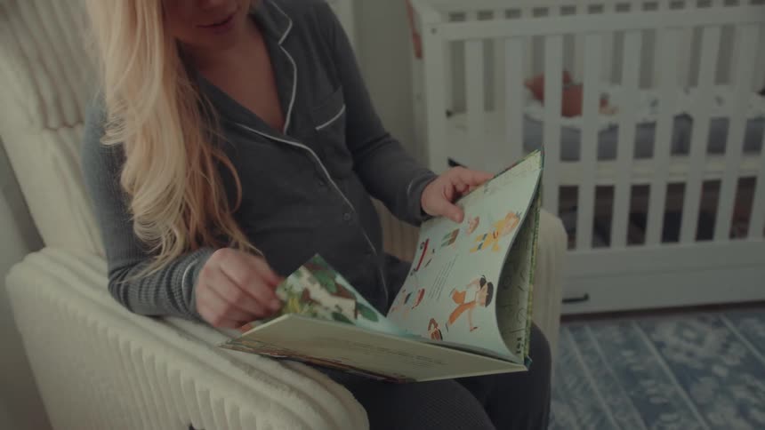 Woman reading book in nursery room