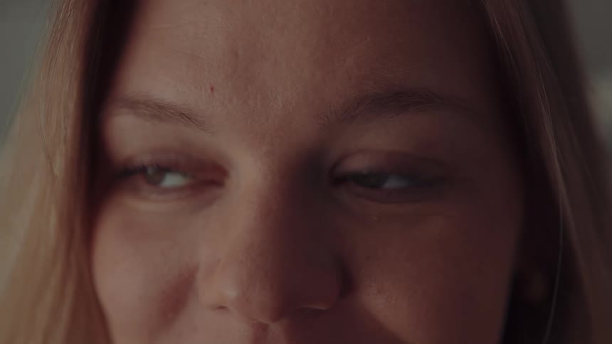 A closeup of a womans face specifically focusing on her eyes and the upper bridge of her nosein the first half of the clip she is looking off to the side with an expectant or curious expression before she slowly lowers her eyelids and closes her ey