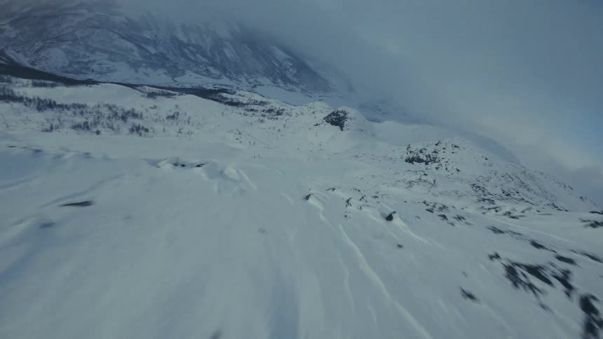 An arctic mountain covered in snow on a foggy day