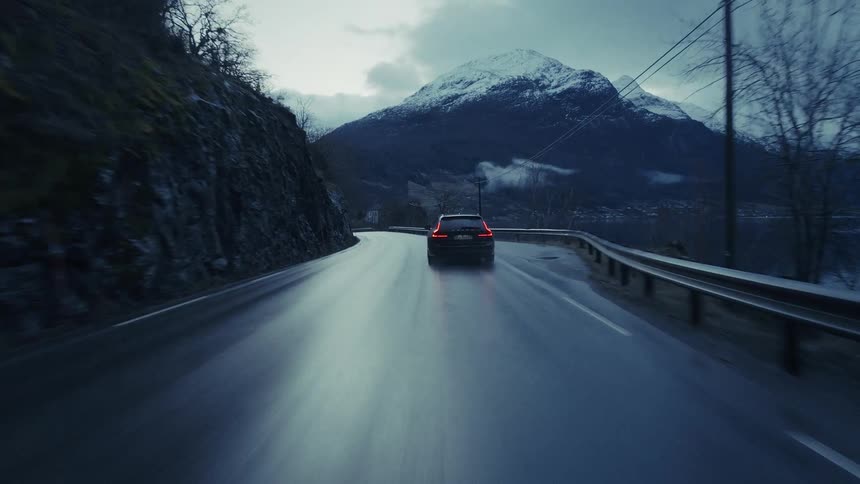 Car driving on a mountain road with a snowcapped peak in the background