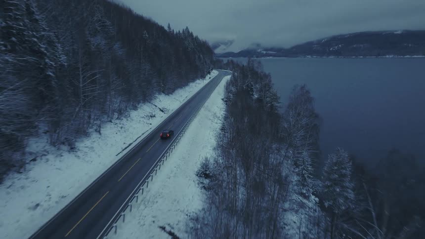 Car traveling on a road along the coast of a forested mountain river valley