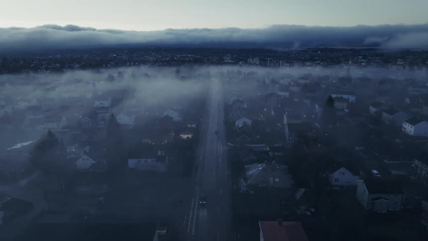 Aerial view of a city covered in fog at dawn