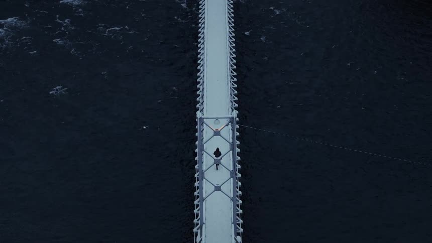 A person walking on a bridge over a river