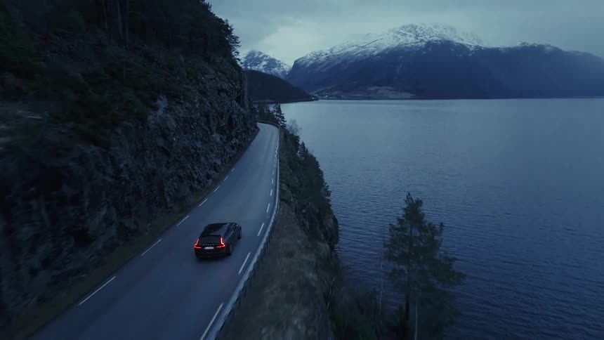 Coastal winding road with cars between snowy mountains