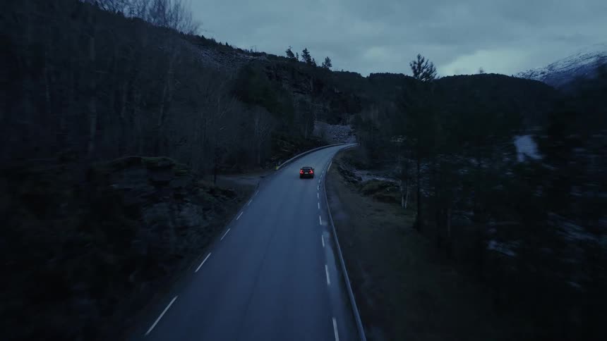Car traveling on a road along the coast of a forested mountain river valley