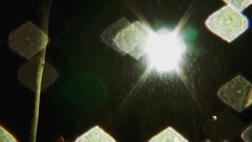 A streetlight illuminating the street at night as rain falls from the sky