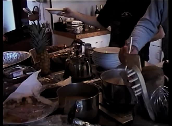 Two people serving food in a kitchen
