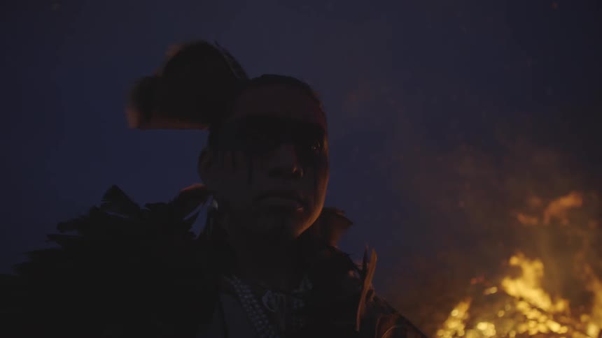 Indigenous person beside a campfire at night