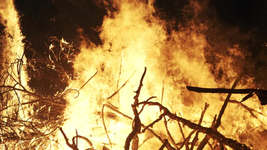 Intense bonfire consuming pile of branches and wood