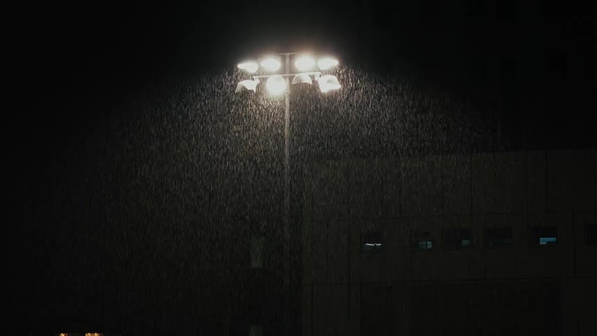 Light pole with floodlights illuminates heavy rain at night