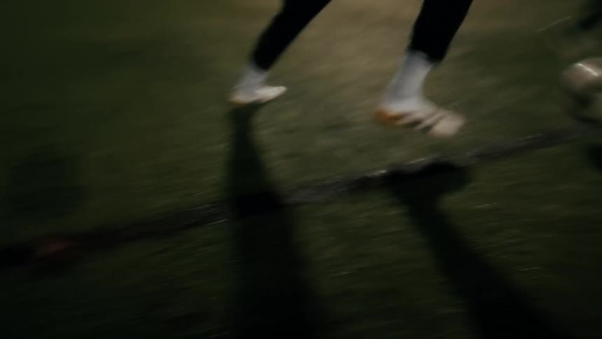 Two people are playing soccer on a sports field at night