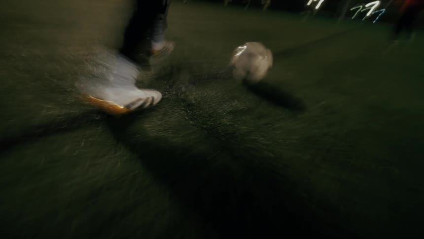 Person dribbles a soccer ball on a lit court at night
