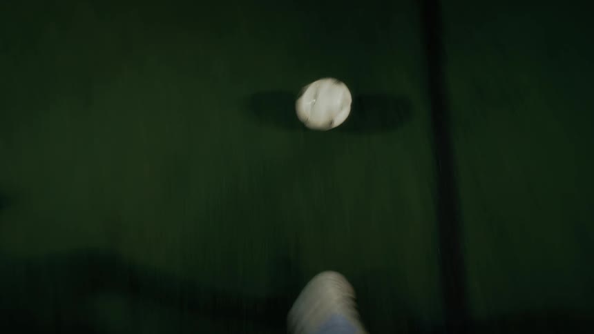Soccer player dribbling a soccer ball on a court and another player kicking the ball away from him indoors