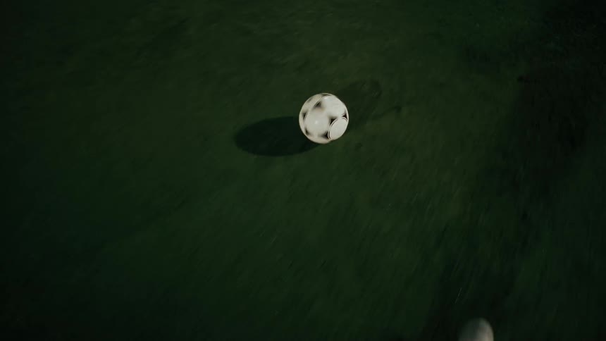 An athlete playing soccer on a field at night