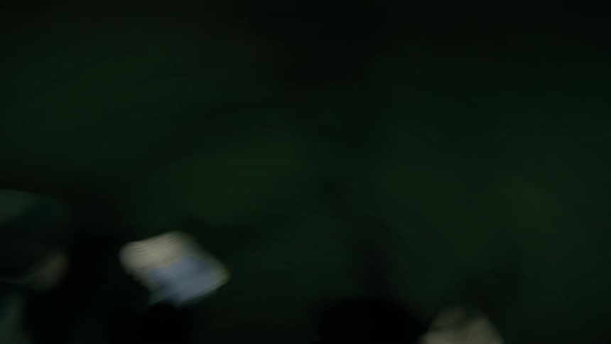 A soccer ball rolls alone across a dark green field as a player kicks the ball under nighttime lighting casting a sharp shadow beneath it