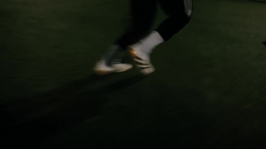 Athletes play soccer on a field in a city at night