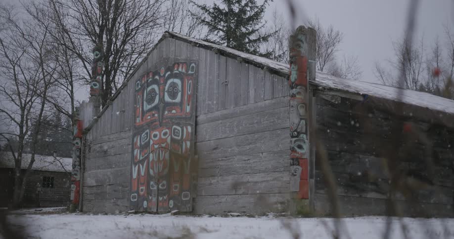 Wooden house with indigenous painting on the facade under light snow