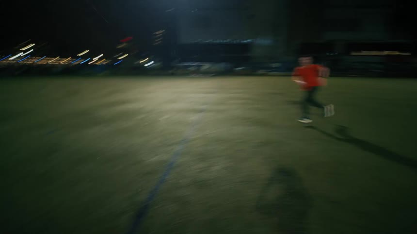 Two people are playing soccer on a sports field at night