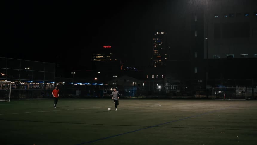 Players competing in soccer match on urban night field