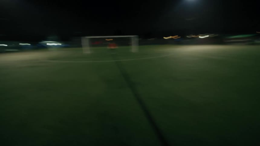 Soccer players on the field as one man kicks the ball toward the goal