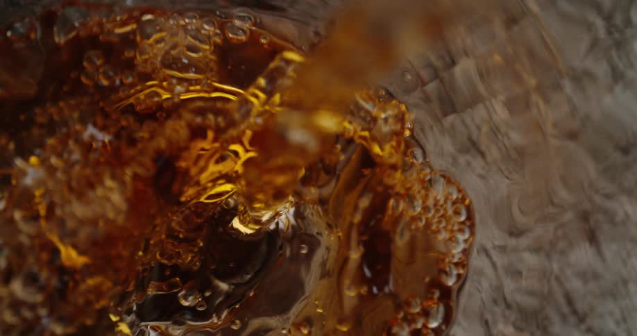 A bottle of whiskey being poured into a glass on a wooden table