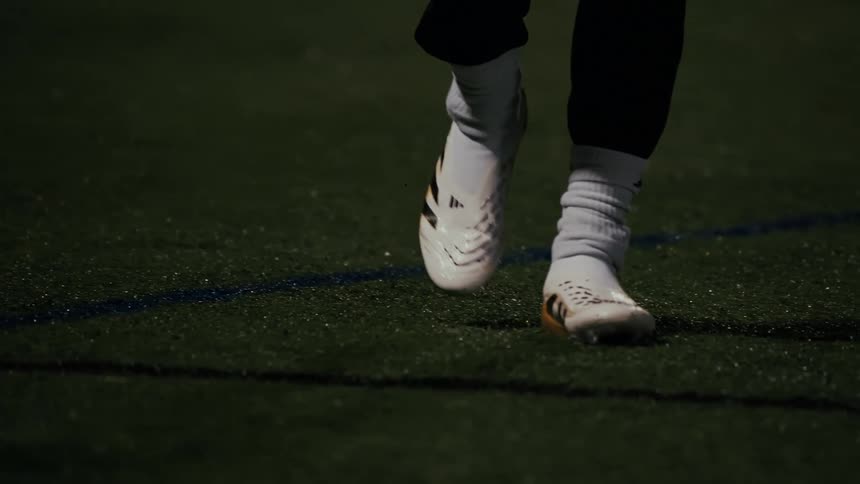 A person walking in soccer cleats at night