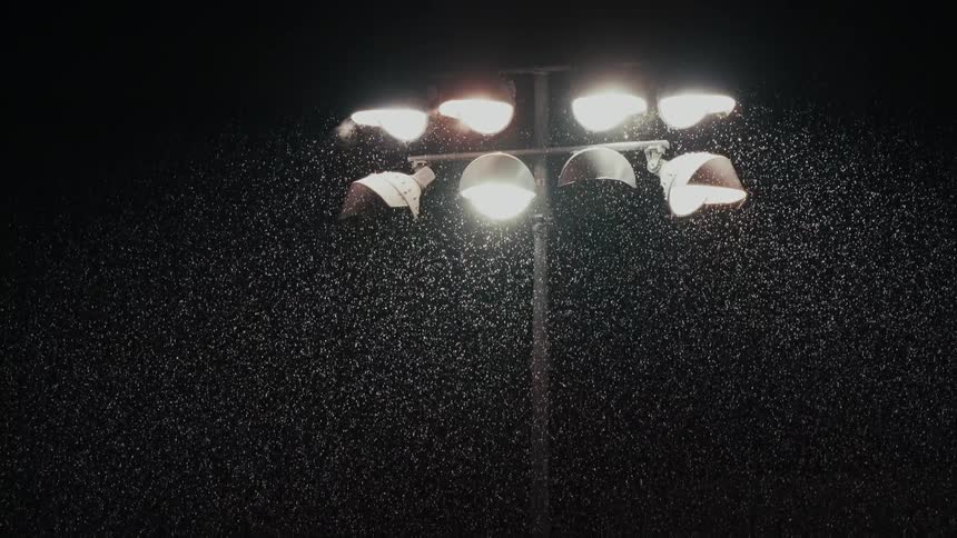 Stadium floodlights illuminate rain at night
