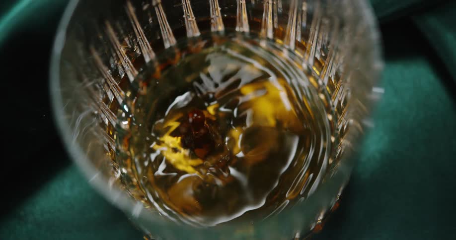 Wine dripping into a glass creating splashes and ripples