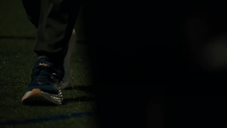 Person dribbling a soccer ball on an artificial turf field at night