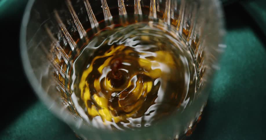 Water droplet falls into a glass and the liquid swirls in a surreal manner