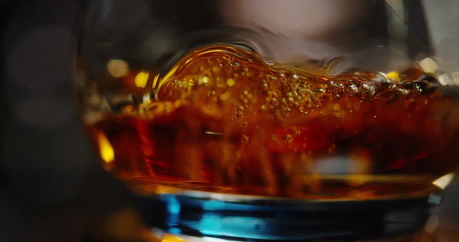Ambercolored alcoholic liquid being poured into a glass