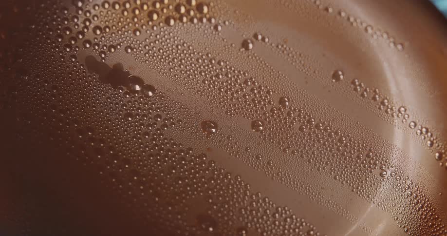 A closeup view of condensation on a warm metallic surface two distinct lines are formed by water droplets merging and trickling down the side