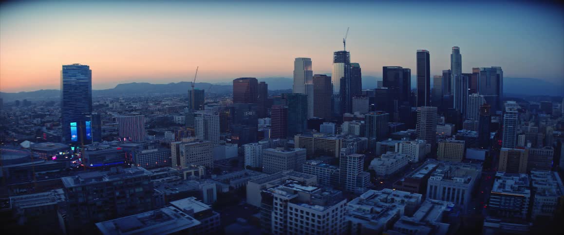 Urban downtown skyline with illuminated skyscrapers at dusk and visible street traffic