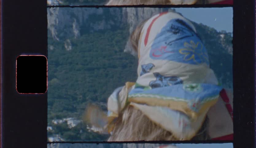 Woman with a colorful headscarf is outdoors with mountains in the background