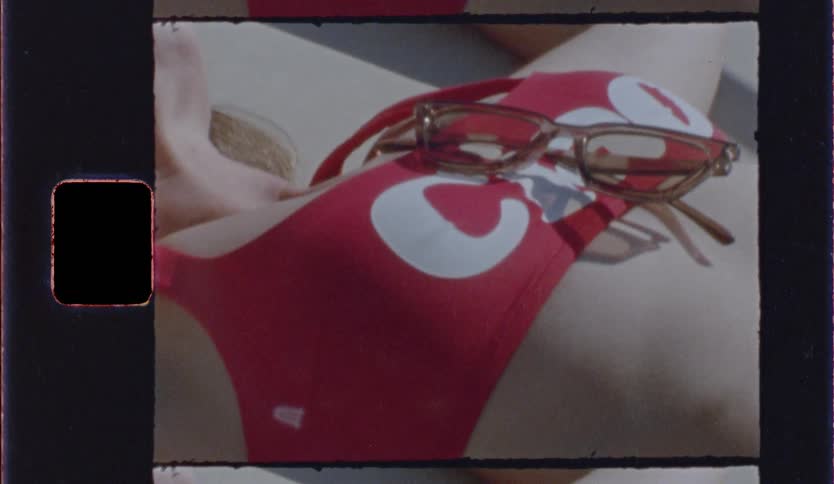Blonde young female lying on the sun wearing a red bikini top outdoors during day time