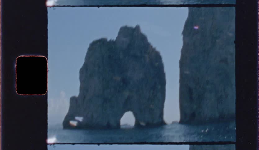 A giant rock formation has a natural archway along an ocean coast