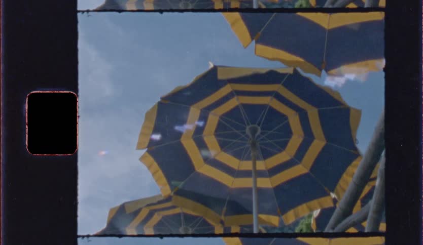 Blue and yellow striped umbrellas seen from below against the sky