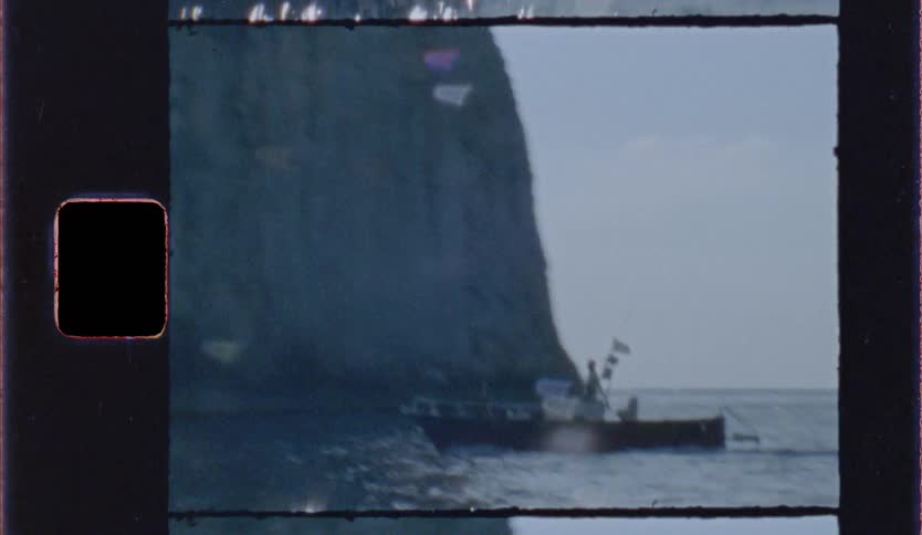 Boat sails near a rock formation in the sea