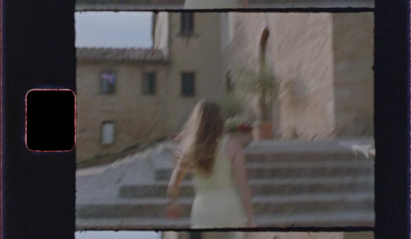 A woman in a light yellow dress playfully twirls and moves toward stone steps in a sunlit europeanstyle courtyard the footage is captured with a vintage film aesthetic featuring a warm grain and visible sprocket holes along the edges of the frame