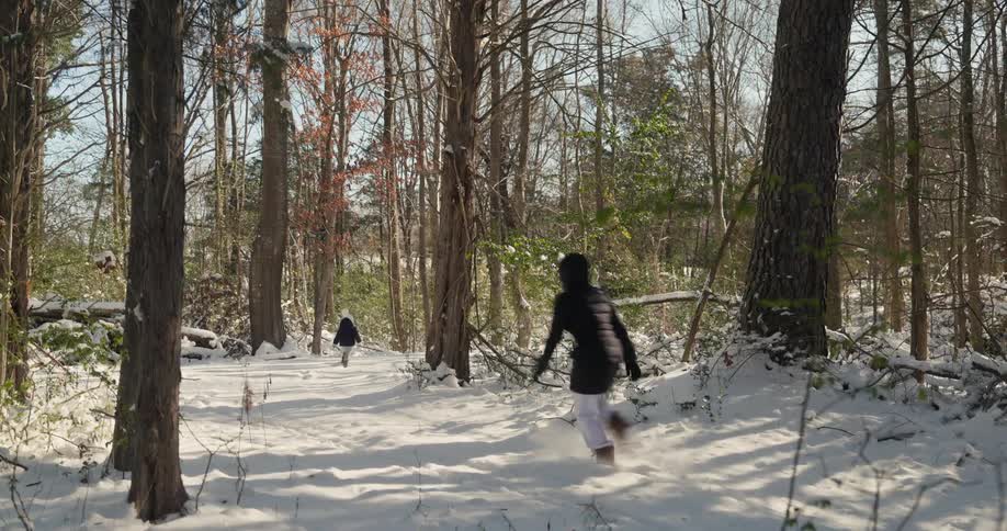 Two people walk along a snowcovered trail in the forest