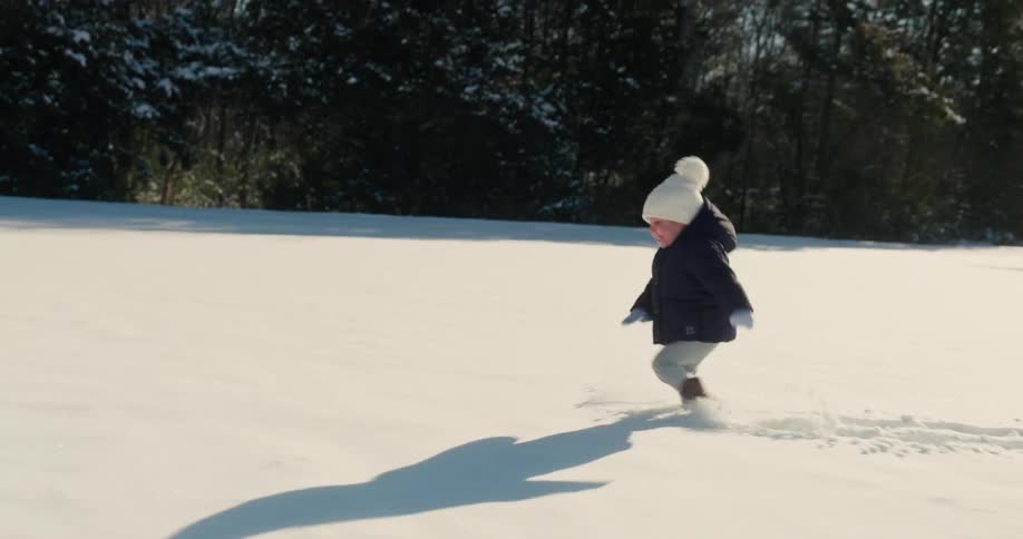 Child walks in the snow in an outdoor park