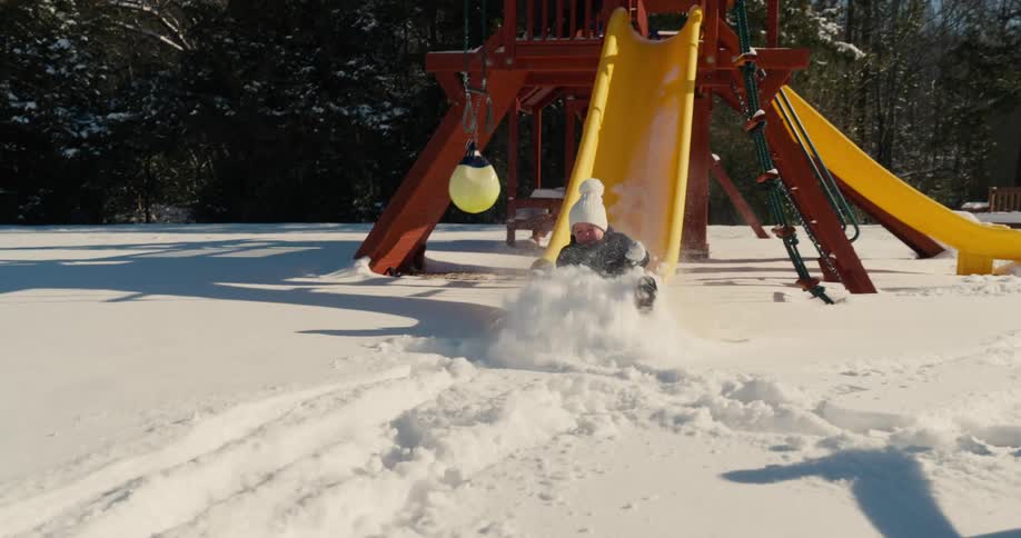 Little boy slides down a snow covered sliding board