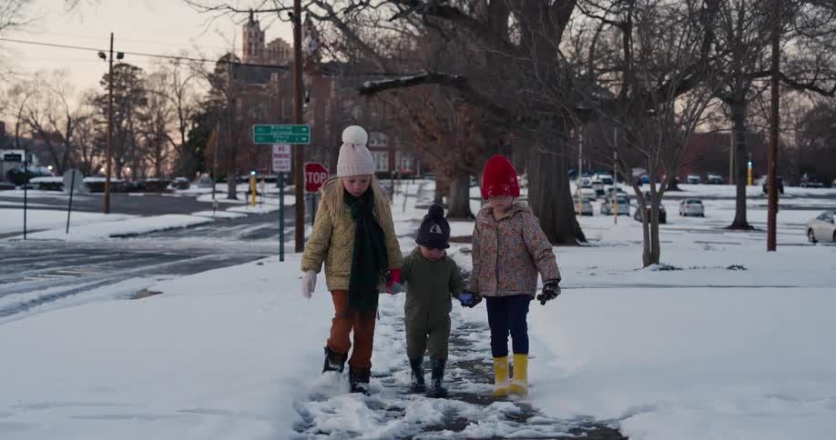 A group of kids walking down a snowy sidewalk