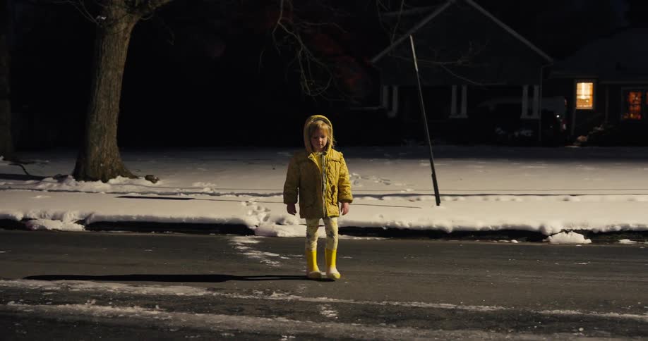 Little girl walks through the snow in front of her house and crosses the street