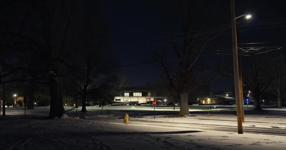 Snow covers the ground as a little girl walks on the sidewalk next to a neighborhood street